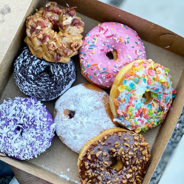 An open box of assorted Donut Factory donuts with various colorful toppings and glazes.