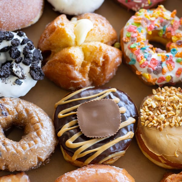 Assortment of Donut Factory donuts, including chocolate peanut butter, glazed, and cereal-topped varieties.