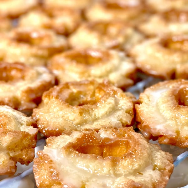 Rows of freshly glazed old-fashioned donuts from Donut Factory, glistening under warm light.