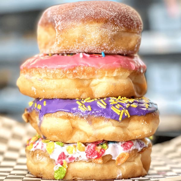 A stack of four colorful donuts from Donut Factory, with various glazes and toppings.