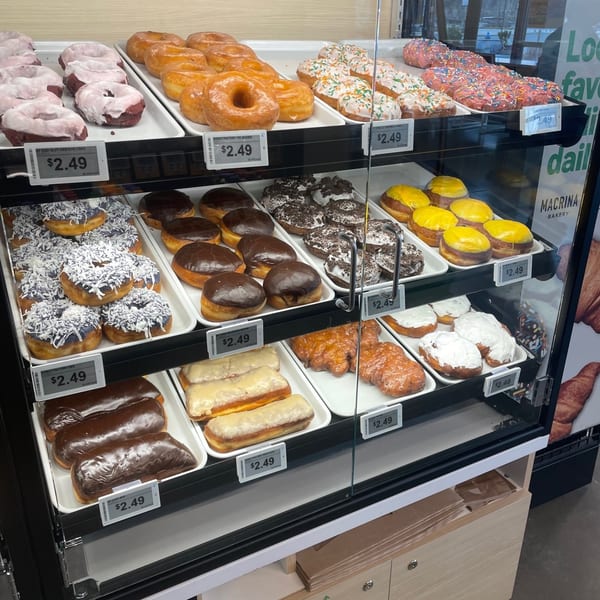 A glass display case at Donut Factory filled with various donuts, including glazed, chocolate, and frosted.
