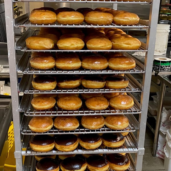 Racks of freshly baked glazed and chocolate-frosted donuts at Donut Factory.